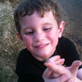A child looking at an insect on his finger.